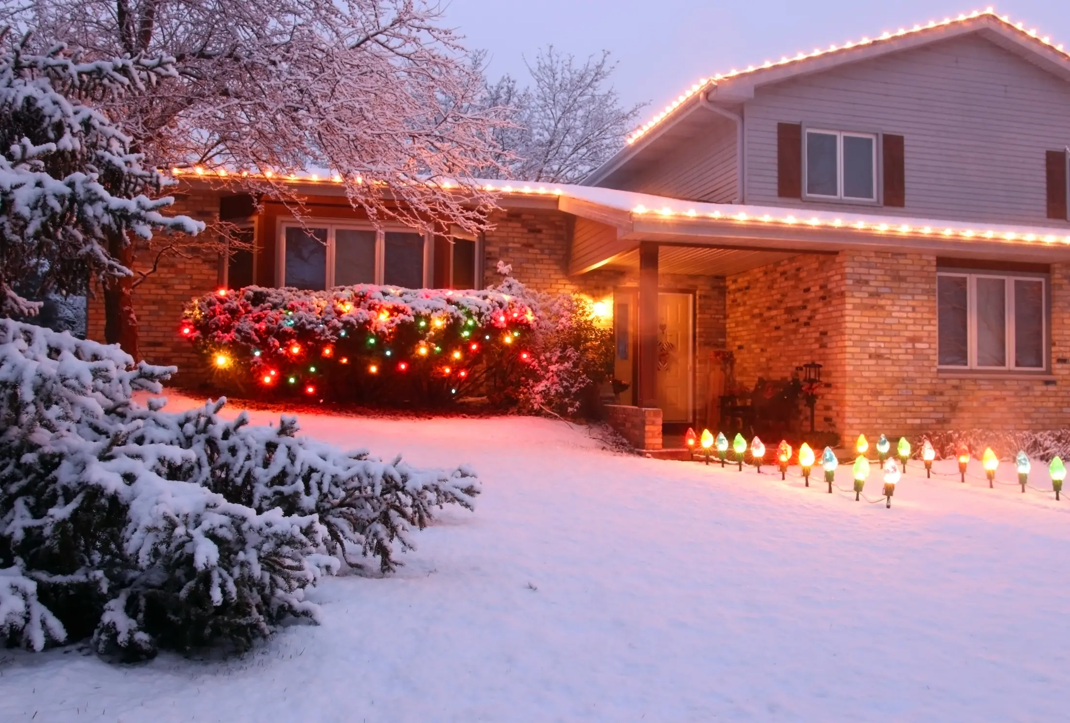 Professional holiday light installer on a roofline ladder